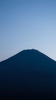 Silhouetted mountain peak against clear blue twilight sky with stars, minimalist landscape composition for nature and travel concepts.
