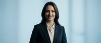 Professional Hispanic businesswoman in dark suit smiling confidently in modern office environment for corporate marketing and leadership concepts.