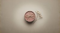Luxury rose gold makeup compact powder with mirror and pearl jewelry on neutral beige background for beauty cosmetics branding and fashion photography.