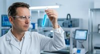 Male scientist in white lab coat examining blue liquid sample in test tube at modern laboratory for research and analysis.