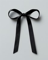 Elegant black satin bow with long trailing ribbons isolated on light gray background, minimalist style suitable for fashion and gift design projects.