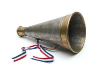 Vintage brass megaphone with red, white and blue ribbons isolated on white background. Retro speaking trumpet for announcements, events, promotions and design projects.