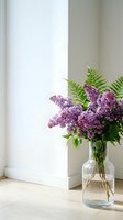 Fresh lilac bouquet with fern leaves in a glass vase on a wooden floor against a white wall in bright natural light.