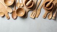 Wooden kitchen utensils and cookware arranged on gray surface. Natural bamboo and wood cooking tools including spoons, bowls, spatulas for culinary use.