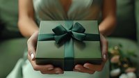 Woman in mint dress holding elegant gift box with dark green ribbon bow for special occasion celebration or holiday present giving.