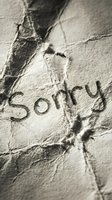 Word sorry written on crumpled aged paper texture, close-up macro shot conveying regret, apology, and emotional concept.