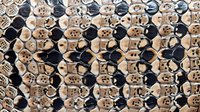 Repeating pattern of black and beige ceramic buttons arranged in rows creating abstract geometric design. Decorative background for fashion and craft projects.