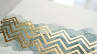 Abstract watercolor background with gold foil chevron pattern overlay creating elegant geometric design for luxury branding and sophisticated decor projects.