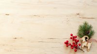 Wooden surface with festive evergreen branch, red berries, and natural twine decoration arranged in corner, suitable for holiday greeting cards and seasonal marketing materials.