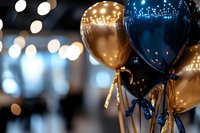 Elegant navy blue and gold balloons with sparkly ribbons against blurred bokeh lights background create festive party atmosphere for celebrations and events.