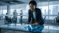 Professional Asian businesswoman analyzing holographic data visualization on interactive table in modern corporate office environment.