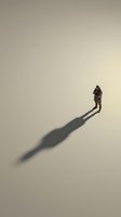 Aerial view of a person in dark clothing standing on a neutral beige surface with a long shadow extending across the ground, suitable for business and motivational concepts.