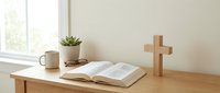 Peaceful morning devotion setup with open Bible, wooden cross, coffee mug and small plant on desk by window. Perfect for faith-based content and spiritual reflection.