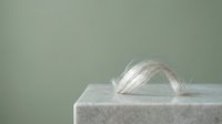 Clear glass ring resting on white marble cube against soft neutral background, showcasing minimalist jewelry design and luxury product presentation.