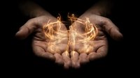 Cupped hands holding glowing golden light energy with magical flames and sparks against dark background for spiritual healing concepts.