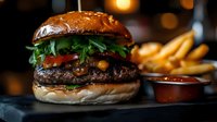 Juicy beef burger with melted cheese, fresh arugula, and bacon on brioche bun served with golden french fries and dipping sauce on dark background with bokeh lights.
