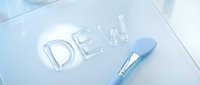 Dental care concept with the word dent formed from clear gel or paste and a blue brush on white surface for oral hygiene and dentistry design projects.