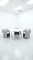 Modern minimalist meeting room with white round table and gray chairs in clean office space for business discussions and corporate presentations.