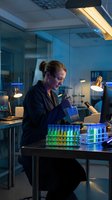 Female scientist working with pipette and test tubes in modern laboratory at night conducting research experiments and chemical analysis.