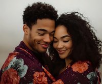 Young African American couple sharing intimate moment, wearing matching floral print outfits. Natural curly hair and genuine smiles create romantic atmosphere.