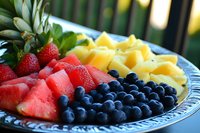 Fresh summer fruit platter with juicy watermelon, ripe strawberries, sweet blueberries and golden pineapple chunks arranged on decorative plate, perfect for healthy eating.
