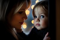 Tender moment between mother and child with bokeh lights creating magical atmosphere. Close up portrait showing emotional connection and gentle care.