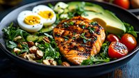 Grilled salmon fillet with avocado, boiled eggs and fresh greens in bowl. Healthy protein-rich meal with vegetables for balanced nutrition and wellness.