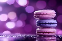Colorful French macarons stacked on glittery surface with purple bokeh background. Pink and violet pastel colors create dreamy confectionery atmosphere.