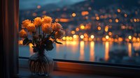 Bouquet of orange roses in glass vase on windowsill with evening cityscape and water reflections in background at twilight.