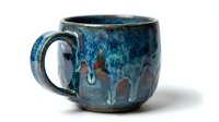 Handmade ceramic mug with blue glaze and rustic drip texture, isolated on white background for product design and e-commerce use.