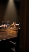 Business professionals analyzing golden holographic financial growth chart with upward trending data visualization in modern conference room setting.