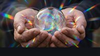 Hands holding transparent crystal ball with rainbow light reflections creating magical prismatic effects for spiritual meditation concepts.