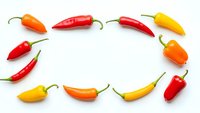 Colorful hot chili peppers arranged in circle on white background. Fresh spicy vegetables for cooking, seasoning and culinary ingredients isolated.