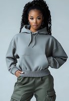 Young African American woman with long curly hair wearing oversized gray hoodie and olive cargo pants poses confidently against light background.