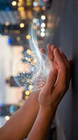 Hands holding glowing digital sphere with light particles and data streams against blurred city lights background representing innovation and technology concepts.