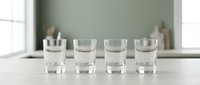 Four clear glasses filled with fresh water arranged on kitchen counter for healthy hydration and daily wellness routine.