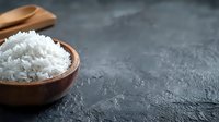 Steamed white jasmine rice served in rustic wooden bowl on dark concrete background with copy space for menu or recipe design.