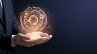 Businessman in suit holding glowing atom hologram, nuclear energy and science innovation concept on dark blue background.