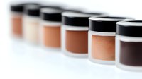 Foundation makeup containers in different skin tone shades arranged in row showing diversity of cosmetic products for professional makeup artists and beauty industry.