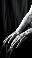 Elderly hands resting gently in dramatic black and white lighting showing wisdom, experience and aging process with detailed skin texture and wrinkles.