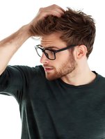Young Caucasian man with glasses scratching head in confusion or stress, wearing casual green shirt isolated on white background for design projects.
