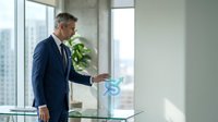 Professional mature Caucasian businessman in navy suit interacting with holographic digital interface in modern office with city view windows.