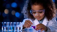 Young African American girl in lab coat and safety glasses conducting science experiment with colorful liquids in test tubes against dark blue bokeh background.
