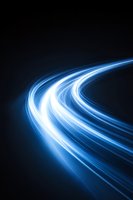 Glowing blue light trails curve through dark space creating dynamic motion effect, suitable for technology and innovation concepts and backgrounds.