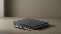 Dark leather-bound notebook with gold pen on neutral beige surface, minimalist workspace setup for business, education, writing, journaling, stationery design projects.