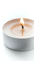 Burning tealight candle with glowing flame and melted wax in white metal holder, isolated on white background for spa and relaxation concepts.