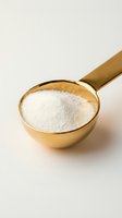 Brass measuring cup filled with white flour powder on neutral background for cooking and baking projects.