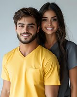 Happy young couple portrait with man in yellow v-neck shirt and woman in gray top smiling together against neutral background for lifestyle content.