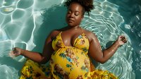 Pregnant African American woman in yellow floral swimsuit floating in turquoise pool water, maternity swimwear fashion and wellness concept.