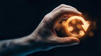 Hand holding glowing golden orb with light particles against dark background, representing energy, innovation, ideas, and future technology concepts for business and design projects.